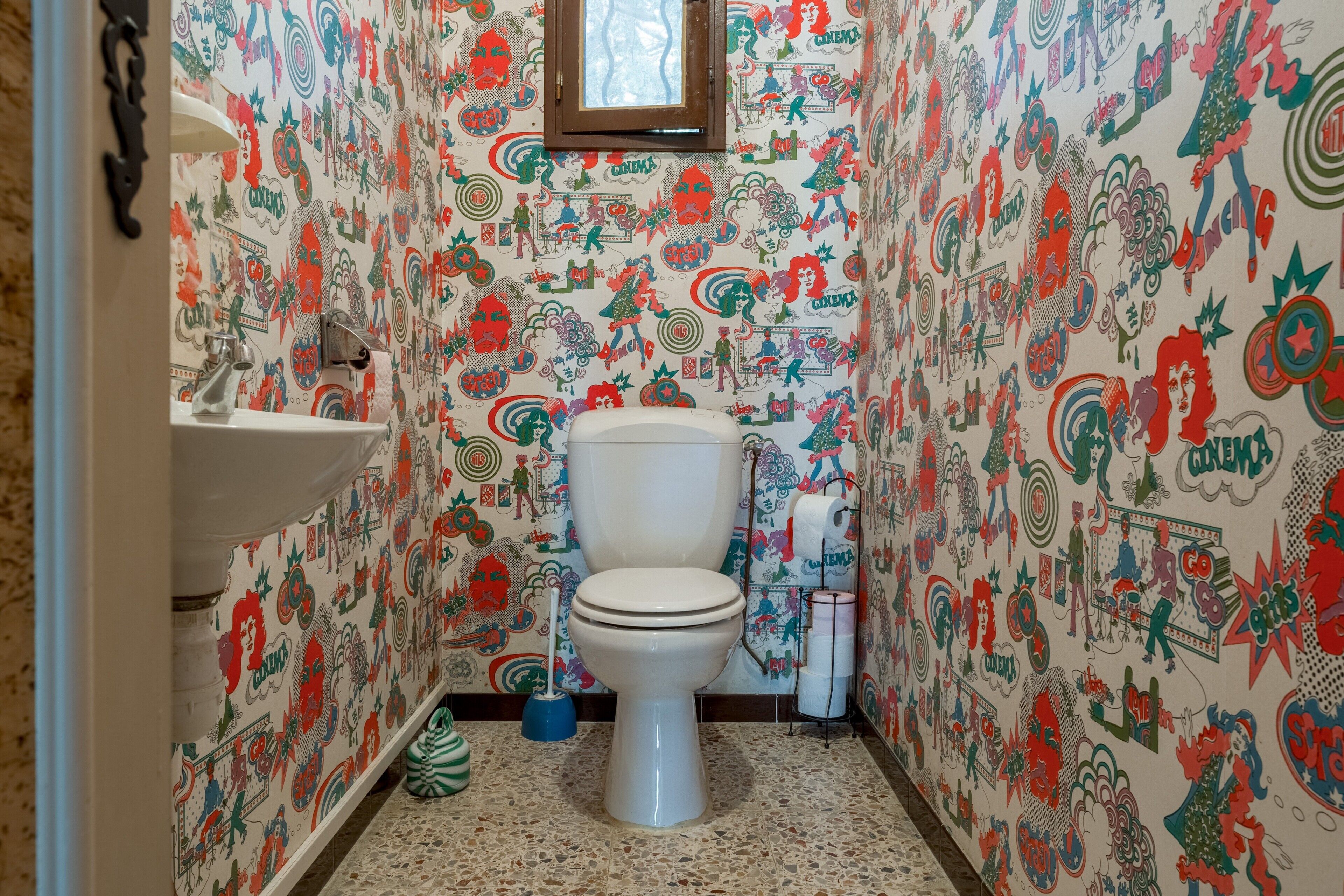 A bathroom with a toilet, sink, and patterned walls.