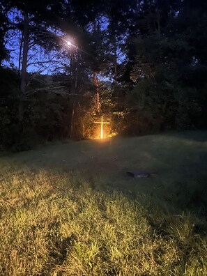 Ein Kreuz, beleuchtet im Gras in der Nacht.