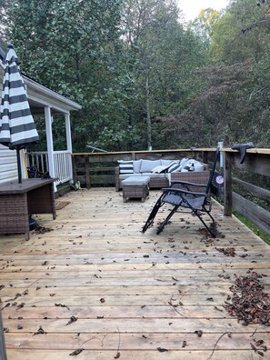 A wooden deck with outdoor furniture, including a sofa and chairs, surrounded by trees. - Christian Home for Retreats, Prayer, Pastors and Missionaries in Hocking Hills (Logan)