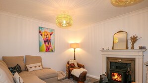 A cozy living room with a beige sofa, a fireplace, a lamp, and a colorful painting on the wall. - Number 5 (Chichester)