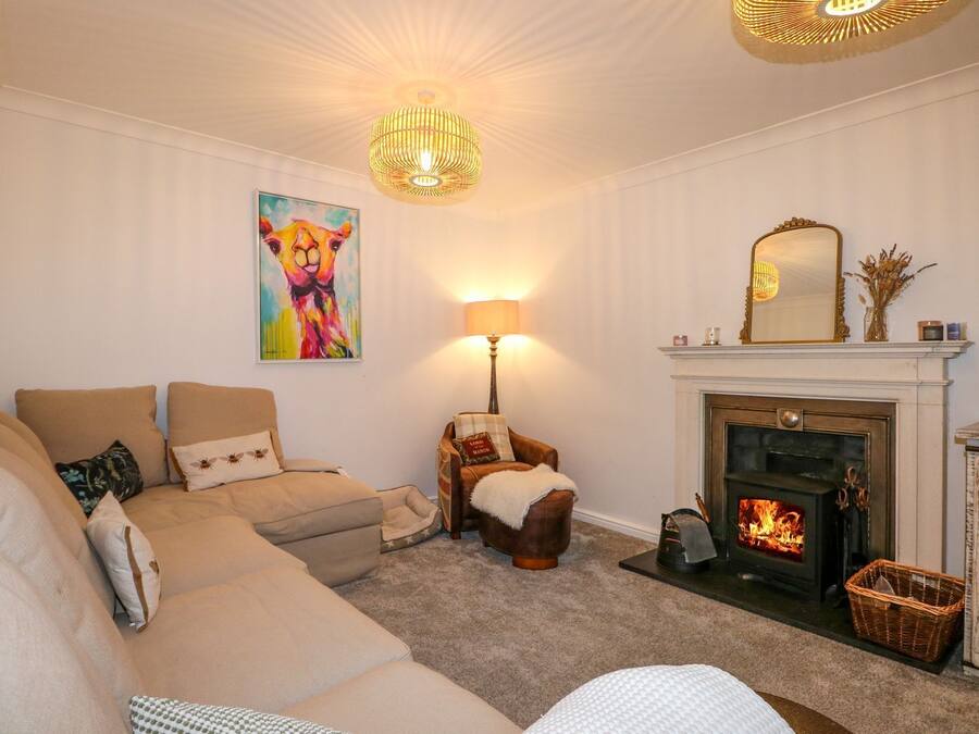 A cozy living room with a beige sofa, a fireplace, a lamp, and a colorful painting on the wall.