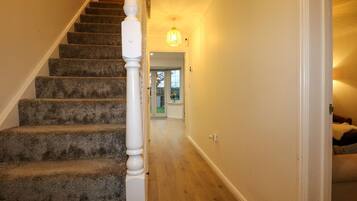 A staircase with carpeted steps and a white balustrade leading to a door.