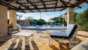 A covered outdoor area with a pool, lounge chairs, and a table. - Hotiday Monopoli Collina (Monopoli)