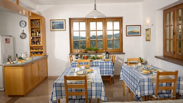 A dining area with a large window, wooden cabinets, and a clock on the wall. - Hotiday Monopoli Collina (Monopoli)