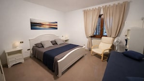 A bedroom with a bed, bedside tables, a chair, a window with curtains, and a wall-mounted artwork. - Hotiday Monopoli Collina (Monopoli)