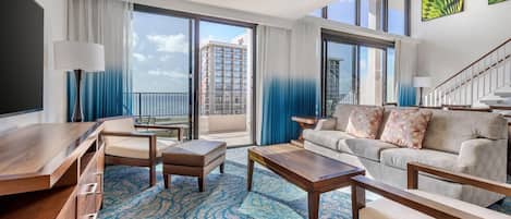 A spacious living room with a balcony, a sofa set, a coffee table, and a TV.