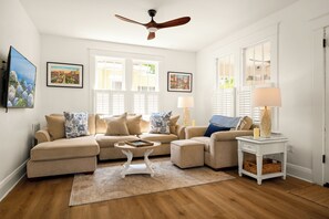 A living room with a ceiling fan, two sofas, a coffee table, and a side table with a lamp. - Dog-Friendly Farmhouse – 4BR Fenced Yard, Porch, Walkable to Restaurants & Cafes (Tampa)