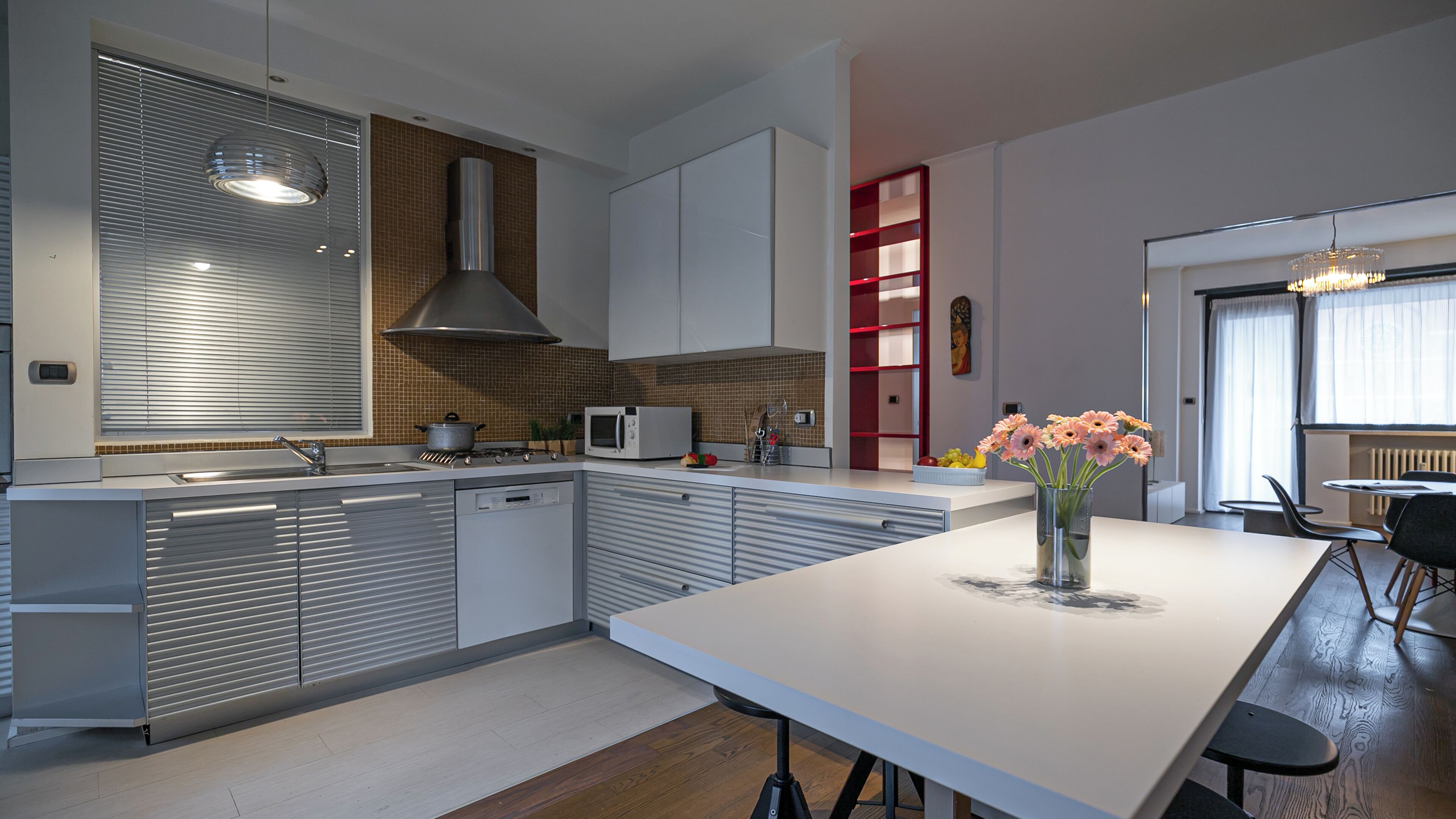 A modern kitchen with a central island, stainless steel appliances, and a red accent wall.