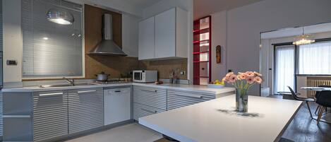 A modern kitchen with a central island, stainless steel appliances, and a red accent wall.