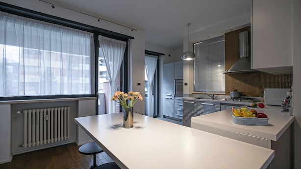 Una cocina moderna con una isla central, un comedor y vistas a la calle.