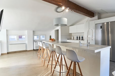 A modern kitchen with a central island, bar stools, a stainless steel refrigerator, and a large window.. Casa Rural Pico Mágina: Your Comfortable Home Away from Home