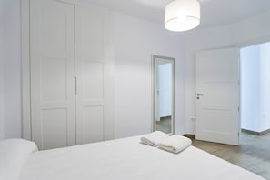 A bedroom with a bed, a wardrobe, a mirror, and a door leading to another room. - Casa Rural Pico Mágina: Your Comfortable Home Away from Home (Albanchez de Mágina)