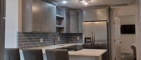 A modern kitchen with a built-in island, stainless steel appliances, and a dark backsplash.