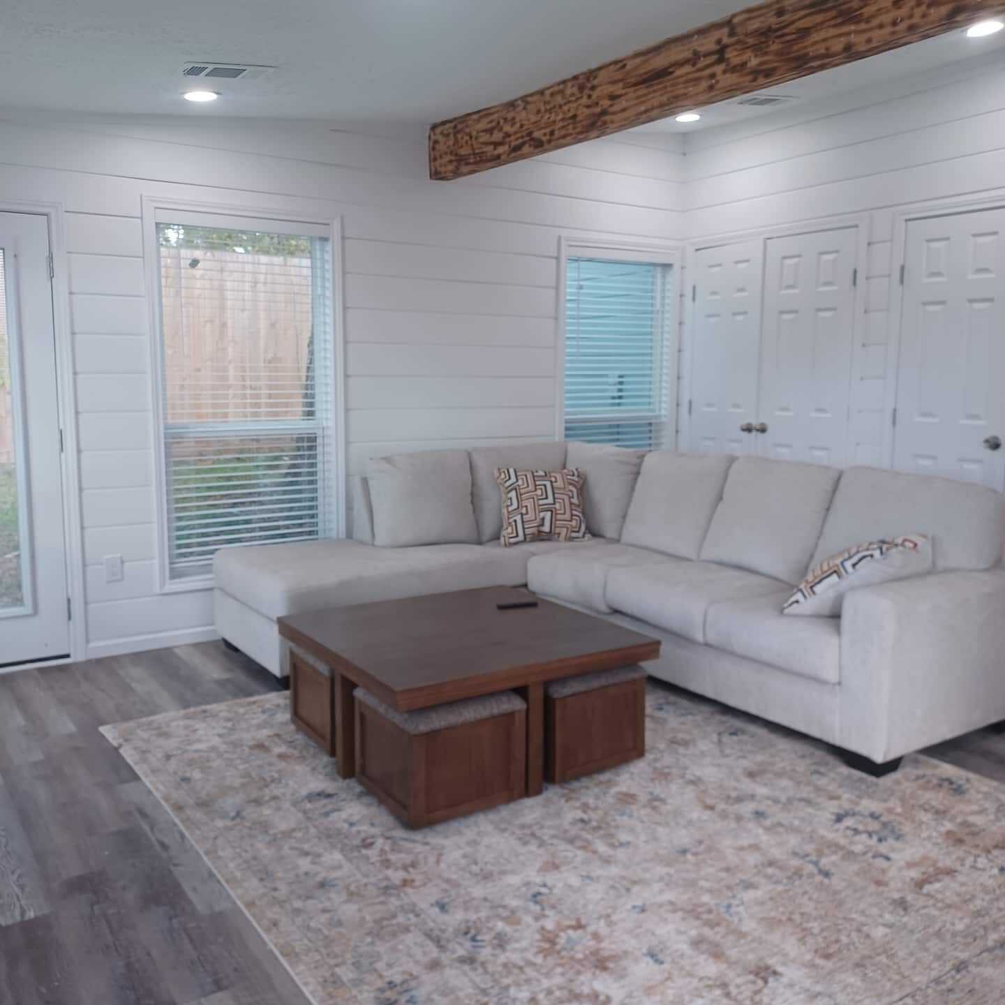 A modern living room with a sectional sofa, a wooden coffee table, and a patterned rug.