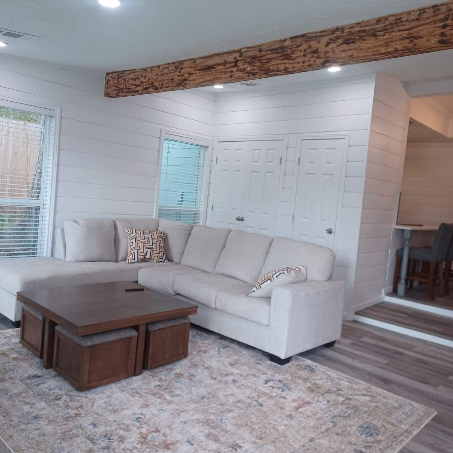 Una sala de estar con un sofá modular, una mesa de centro de madera y una alfombra estampada.
