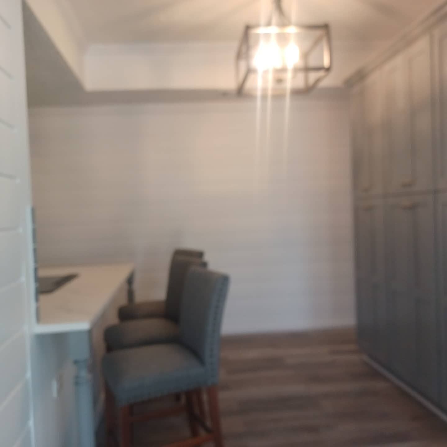 Una habitación con una mesa de comedor y sillas, una lámpara colgante y un armario.
