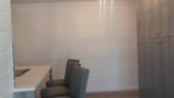 Una habitación con una mesa de comedor y sillas, una lámpara colgante y un armario.