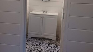 Une salle de bain avec un meuble-lavabo blanc, un miroir rond et un carrelage à motifs.
