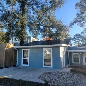 A residential house with a blue exterior, a wooden fence, and a large tree in the background. - Enjoy the entire private cottage with two comfortable bedrooms, a fully equipped kitchen, spacious living room, full bathroom, and in-unit washer and dryer. Relax with an 85-inch Smart TV, fast Wi-Fi, and comfortable furnishings throughout. (Conroe)