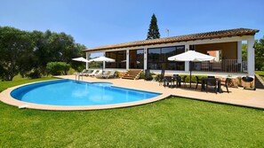 Une maison moderne dotée d’une piscine, d’un espace salon extérieur et d’un patio couvert.