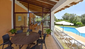 Un espace extérieur abrité, aménagé pour les repas, avec une piscine et des parasols.
