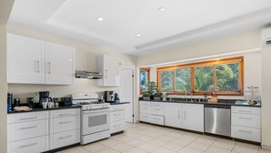 Una cucina moderna con mobili bianchi, forno integrato e lavastoviglie in acciaio inossidabile.