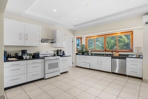 A modern kitchen with white cabinetry, a built-in oven, and a stainless steel dishwasher. - Steps from the beach • Ocean view villa (Noord)
