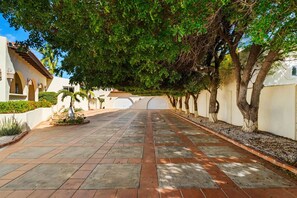 A paved pathway lined with trees and white buildings with arches. - Steps from the beach • Ocean view villa (Noord)