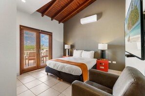 A bedroom with a bed, two bedside lamps, a red nightstand, and a large window with blinds. - Ocean-View Villa w/ Pool, Walk to Boca Catalina (Noord)