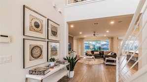 Ein modernes Wohnzimmer mit einer Sofagarnitur, einem Couchtisch und einem Bücherregal mit Büchern und einem Schild mit der Aufschrift 'PARIS'.