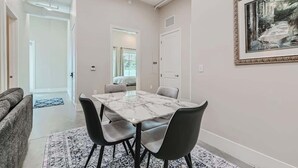 A modern dining area with a marble table and grey chairs, a patterned rug, and a framed picture on the wall. - Golden Getaway | Spacious 2BR | Walk to Trails (Golden)