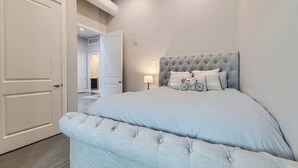 A bedroom with a tufted headboard, a bed with a light-colored duvet, and a bicycle decoration on the bed. - Golden Getaway | Spacious 2BR | Walk to Trails (Golden)
