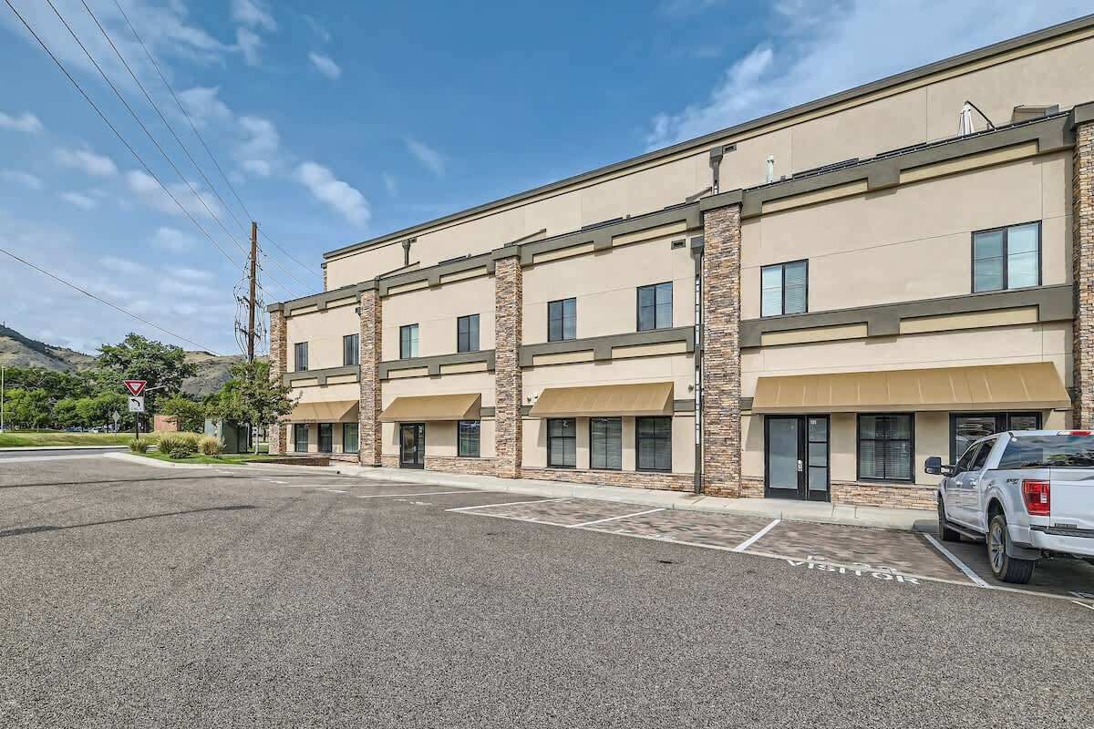 A multi-story building with a flat facade, large windows, and a parking lot with marked spaces.