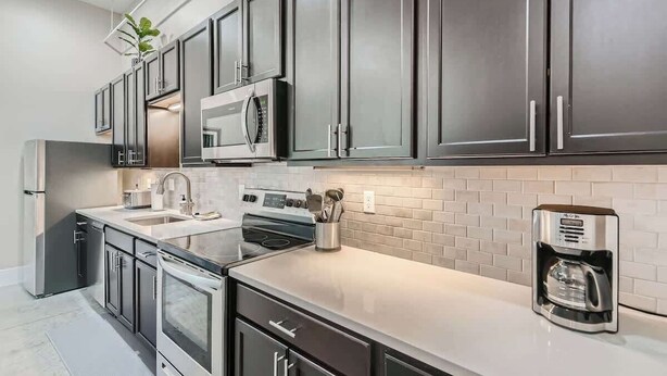 A modern kitchen with stainless steel appliances, dark cabinets, and a white countertop. - Golden Getaway | Spacious 2BR | Walk to Trails (Golden)