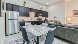 A modern kitchen with dark cabinets, a stainless steel refrigerator, and a marble-top dining table with chairs. - Golden Getaway | Spacious 2BR | Walk to Trails (Golden)