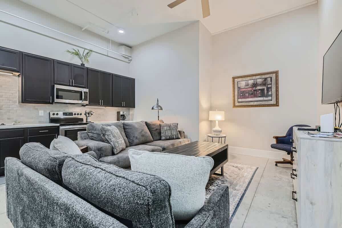 A modern living room with a grey sectional sofa, a coffee table, and a TV stand.
