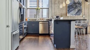 A modern kitchen with grey cabinets, stainless steel appliances, and a large window. - Art Lover's Dream: 2BD Luxury 30+ Day, Coors Field (Denver)