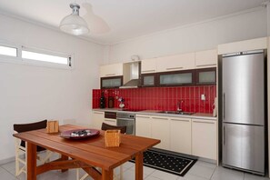Eine moderne Küche mit Holztisch, Edelstahlkühlschrank und roten Fliesen als Rückwand.