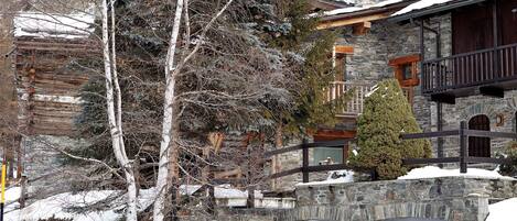 Ein Steinhaus mit einem Balkon, Holzgeländern und einem mit Schnee bedeckten Dach.