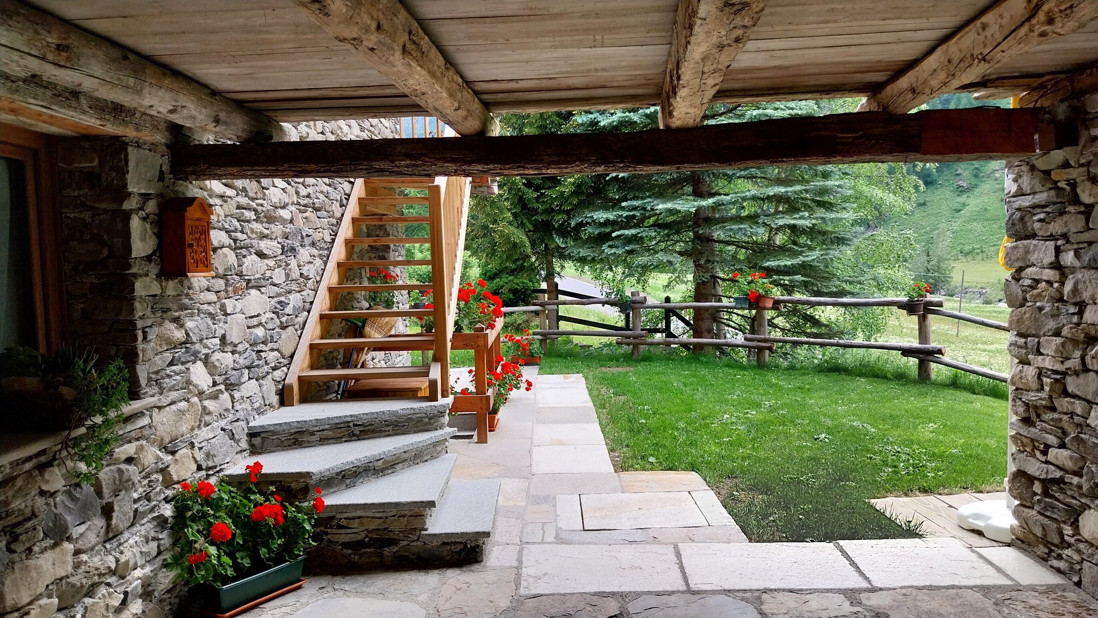 A stone staircase leading to a wooden deck with a view of a grassy yard and a wooden fence.
