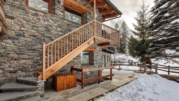 Ein Steinhaus mit einer Holztreppe und einem Balkon.