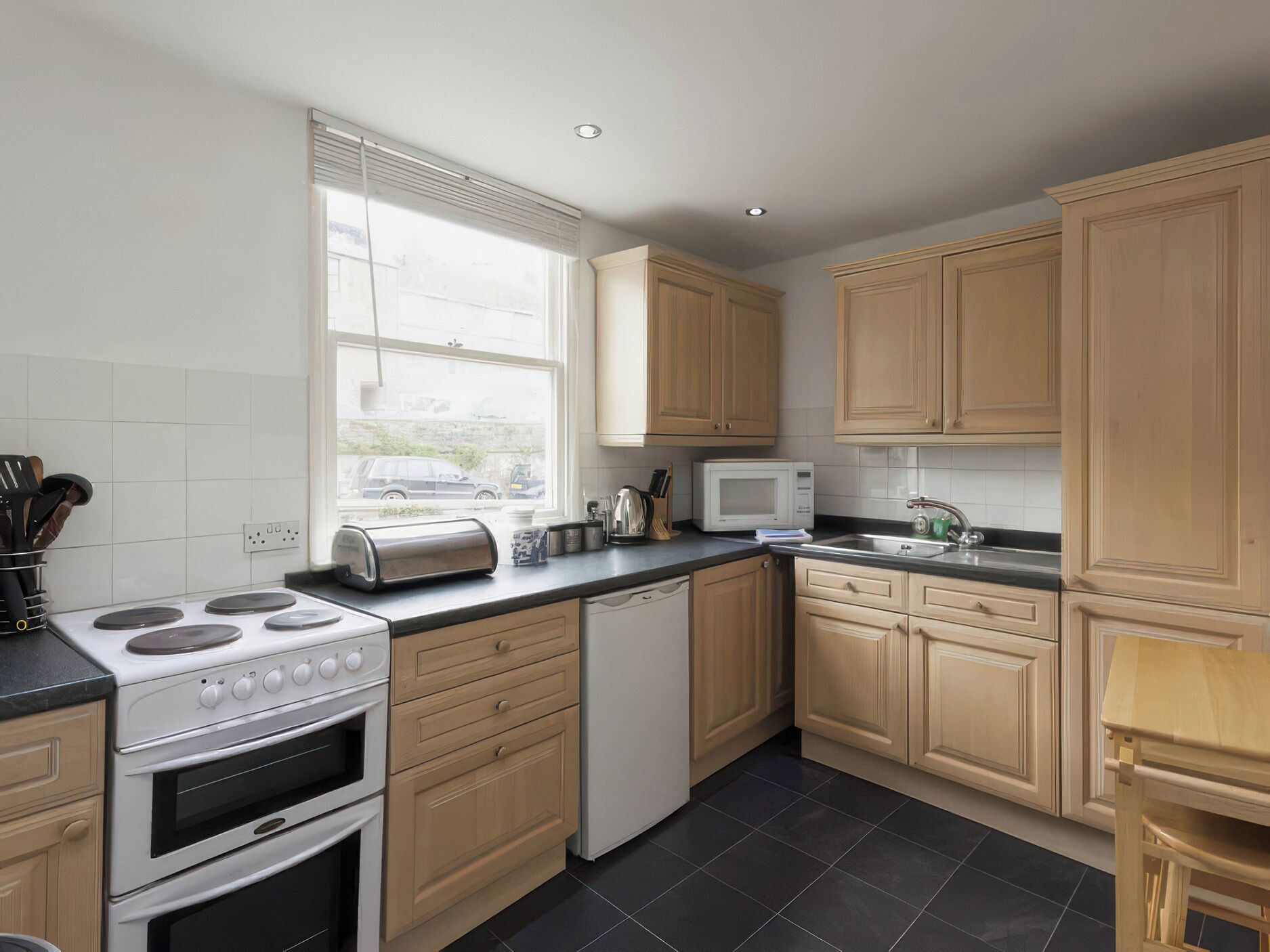 A kitchen with a stove, microwave, toaster, sink, and cabinets.
