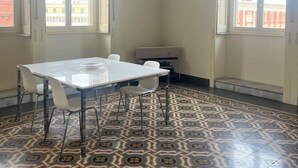 Habitación con una mesa grande y sillas, baldosas de piso estampadas y ventanas amplias con vistas a edificios.