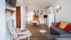 Un espace de vie compact comprenant un coin repas, un canapé, un téléviseur et une cuisine.