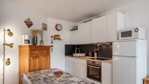 Une cuisine de taille réduite, avec des meubles blancs, un four à micro-ondes, une machine à café et un évier.