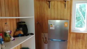 Une cuisine équipée d’un réfrigérateur en acier inoxydable, de meubles de rangement en bois et d’un sol carrelé.