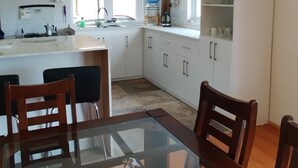 Une cuisine moderne avec des meubles blancs, une table à manger avec des chaises et un îlot de cuisine.