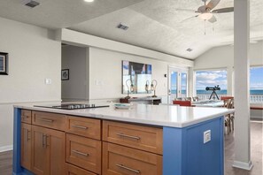 Una cocina amplia con una isla grande, armarios de madera y vistas al exterior.