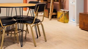 Un coin repas avec une table et des chaises en bois, une lampe, un téléviseur et une bibliothèque.