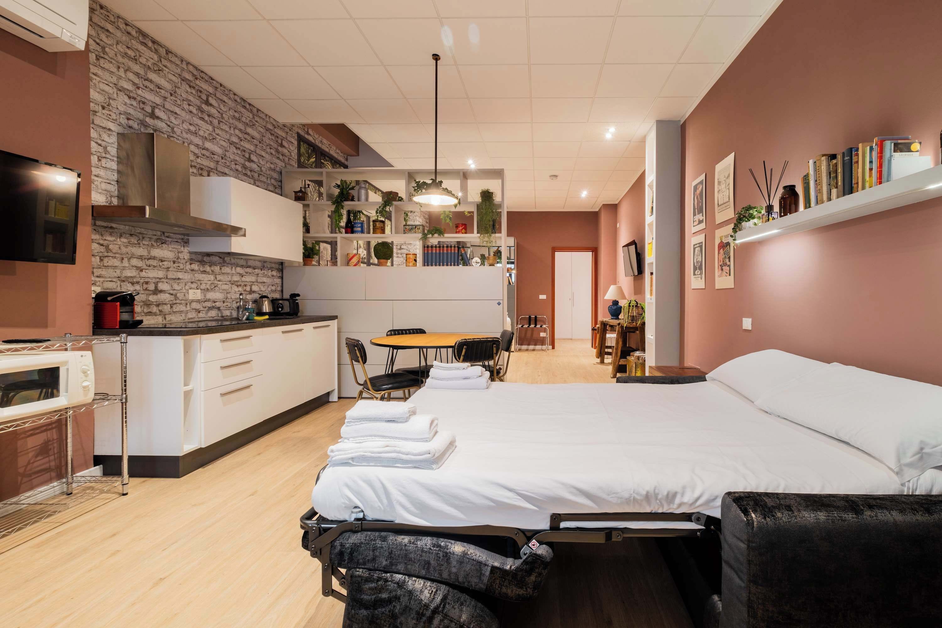 Ein modernes Hotelzimmer mit einem großen Bett, einer Küchenzeile, einem Essbereich und einem Wohnbereich.